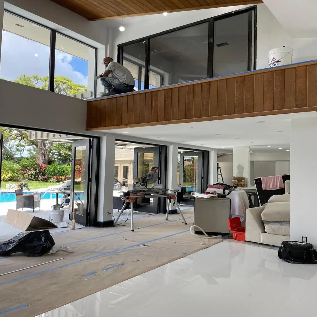 Modern two-story living room with wood ceiling and pool view by JC General Painting in South Florida